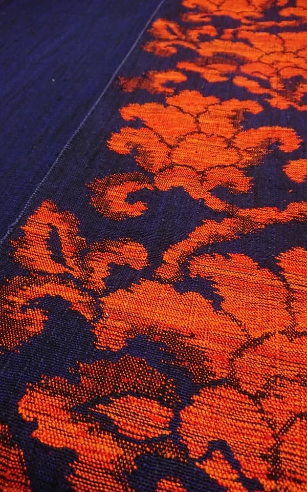 濃い藍色に鮮やかなオレンジが映える手織りの帯
